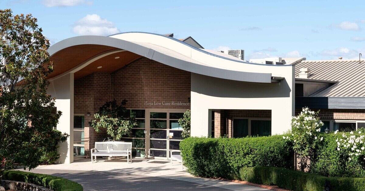 he entrance of a modern care facility with a distinctive curved roof feature.