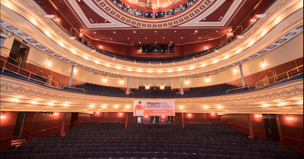 View from a stage overlooking the empty seats and balconies of an ornate red theatre.